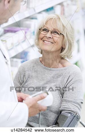 Male pharmacist checking smiling senior female patient's blood pressure in pharmacy. View Large Photo Image Stock Image - Male pharmacist checking smiling senior female patient's blood pressure in pharmacy.. Fotosearch