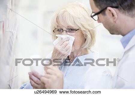 Stock Photo - Male pharmacist giving medicine to sick senior woman.. Fotosearch
