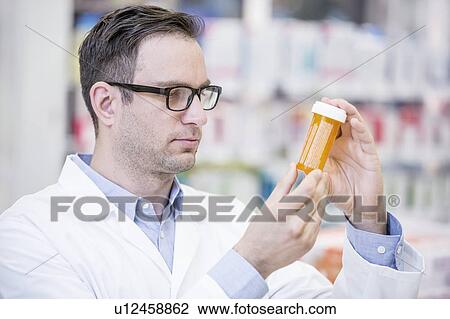 Male pharmacist reading label on pill bottle in pharmacy. View Large Photo Image Stock Image - Male pharmacist reading label on pill bottle in pharmacy.. Fotosearch