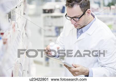 Male pharmacist using digital tablet to check pill bottle in pharmacy. View Large Photo Image Stock Image - Male pharmacist using digital tablet to check pill bottle in pharmacy.. Fotosearch
