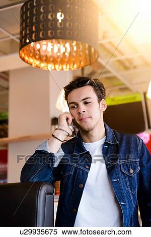 Stock Photography - Male student making smartphone call in cafe. Fotosearch