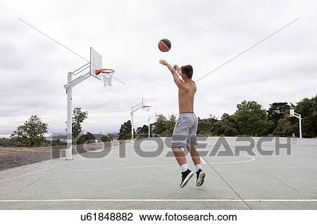 Male teenage basketball player jumping and throwing ball toward basketball hoop View Large Photo Image Stock Image - Male teenage basketball player jumping and throwing ball toward basketball hoop. Fotosearch