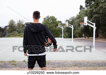 Male teenage basketball player looking out over basketball court, rear view View Large Photo Image Stock Image - Male teenage basketball player looking out over basketball court, rear view. Fotosearch