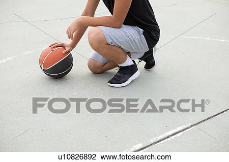 Male teenage basketball player crouching with ball on basketball court, neck down View Large Photo Image Stock Image - Male teenage basketball player crouching with ball on basketball court, neck down. Fotosearch