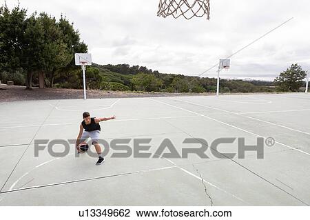 Male teenage basketball player practicing with ball near basketball hoop View Large Photo Image Stock Image - Male teenage basketball player practicing with ball near basketball hoop. Fotosearch