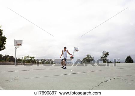 Male teenage basketball player practicing with ball on basketball court View Large Photo Image Stock Photo - Male teenage basketball player practicing with ball on basketball court. Fotosearch