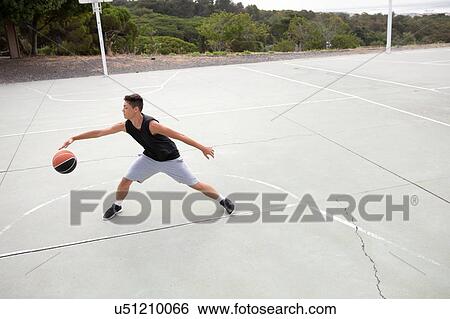 Stock Photograph - Male teenage basketball player practicing on basketball court. Fotosearch