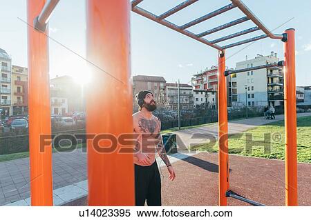 Stock Photography - Man contemplating horizontal ladder in outdoor gym. Fotosearch