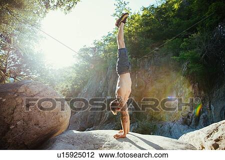 Stock Image - Man doing handstand on rock, Arezzo, Toscana, Italy. Fotosearch