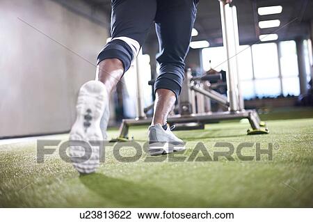 Stock Image - Man doing sled training in gym. Fotosearch