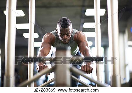 Stock Photo - Man doing sled training in gym. Fotosearch