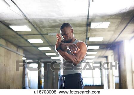 Stock Photo - Man doing stretching exercise in gym. Fotosearch