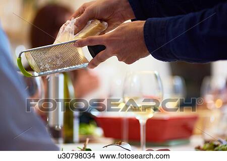Man grating cheese at dinner party View Large Photo Image Picture - Man grating cheese at dinner party. Fotosearch