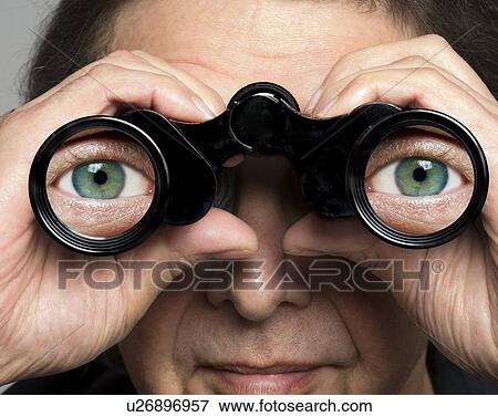 Stock Photo - Man holding binoculars with eyes on lenses. Fotosearch