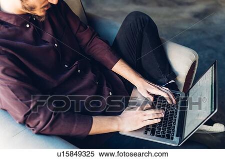Man in armchair using laptop View Large Photo Image Stock Photography - Man in armchair using laptop. Fotosearch