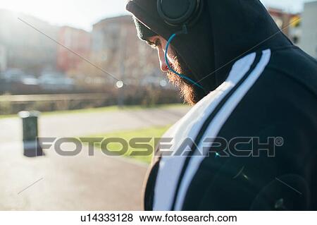 Man in hoodie using headphones View Large Photo Image Stock Photo - Man in hoodie using headphones. Fotosearch