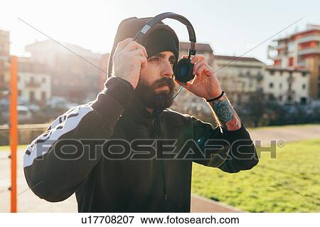 Stock Photo - Man in hoodie using headphones. Fotosearch