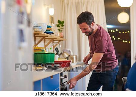 Picture - Man in kitchen at dinner party. Fotosearch