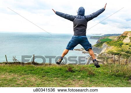 Man jumping on clifftop by sea, Bournemouth, UK View Large Photo Image Stock Photograph - Man jumping on clifftop by sea, Bournemouth, UK. Fotosearch