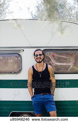 Stock Photograph - Man leaning against caravan. Fotosearch