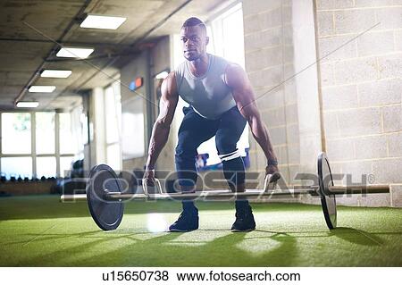 Stock Photo - Man lifting barbell in gym. Fotosearch