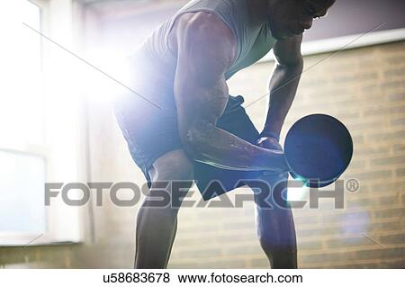 Stock Photo - Man lifting dumbbell in gym. Fotosearch