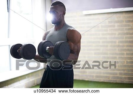 Man lifting dumbbells in gym View Large Photo Image Picture - Man lifting dumbbells in gym. Fotosearch