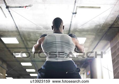 Stock Photo - Man lifting kettlebells in gym. Fotosearch