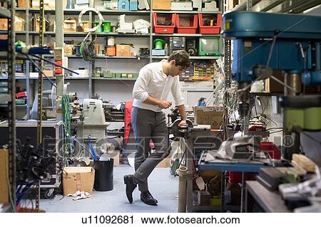 Stock Image - Man looking at work station in workshop. Fotosearch