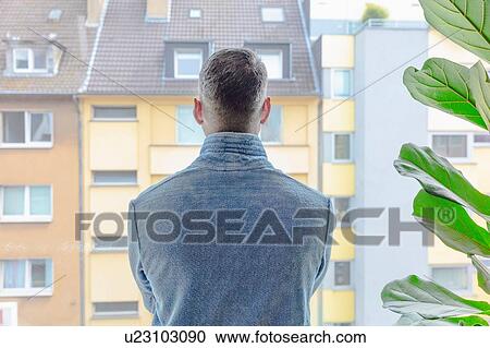 Man looking out of window at apartment block View Large Photo Image Stock Image - Man looking out of window at apartment block. Fotosearch