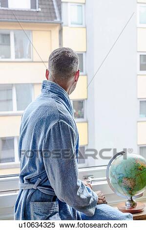Man looking out of window at apartment block View Large Photo Image Stock Photography - Man looking out of window at apartment block. Fotosearch