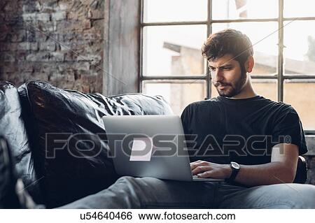 Man on sofa using laptop View Large Photo Image Stock Photograph - Man on sofa using laptop. Fotosearch