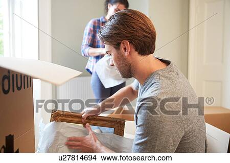 Picture - Man packing mirror into cardboard box. Fotosearch
