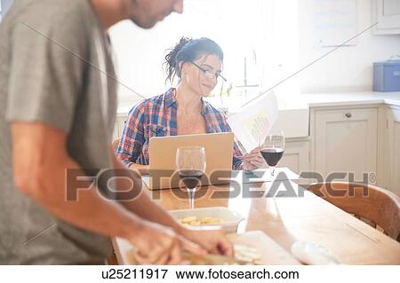 Man preparing vegetables at kitchen table, girlfriend reading paperwork View Large Photo Image Stock Photo - Man preparing vegetables at kitchen table, girlfriend reading paperwork. Fotosearch