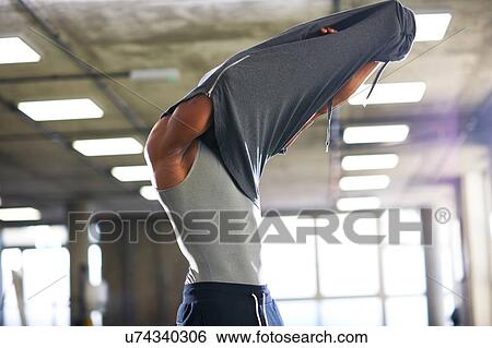 Stock Photograph - Man putting on hoodie in gym. Fotosearch