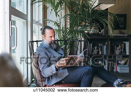 Stock Image - Man reading on armchair. Fotosearch