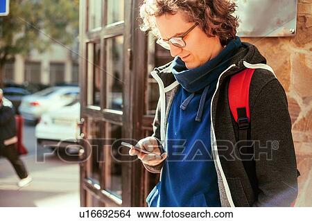 Picture - Man reading text message by door. Fotosearch