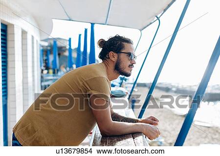 Man relaxing under canopy at sea, Livorno, Italy View Large Photo Image Picture - Man relaxing under canopy at sea, Livorno, Italy. Fotosearch