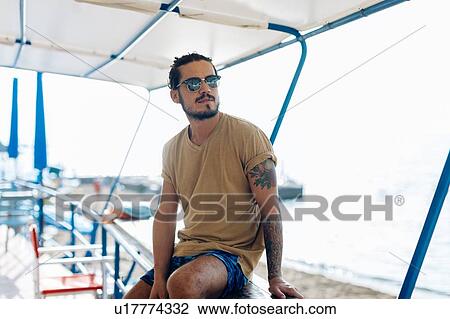 Man relaxing under canopy at sea, Livorno, Italy View Large Photo Image Stock Image - Man relaxing under canopy at sea, Livorno, Italy. Fotosearch