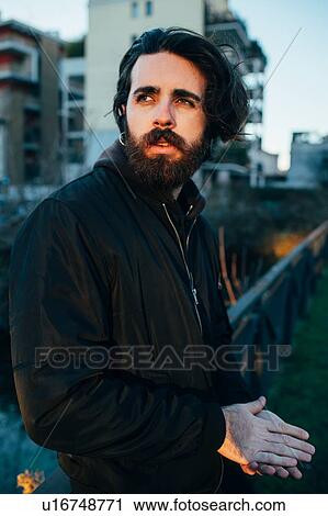 Stock Image - Man rubbing hands warm in park. Fotosearch