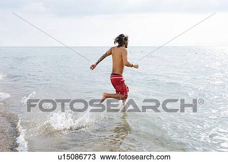 Stock Image - Man running into sea. Fotosearch