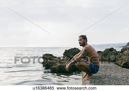 Man sitting on edge of sea View Large Photo Image Stock Photography - Man sitting on edge of sea. Fotosearch