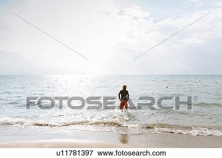 Man standing at edge of sea View Large Photo Image Stock Photo - Man standing at edge of sea. Fotosearch
