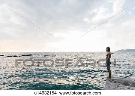 Man standing on edge of sea View Large Photo Image Picture - Man standing on edge of sea. Fotosearch