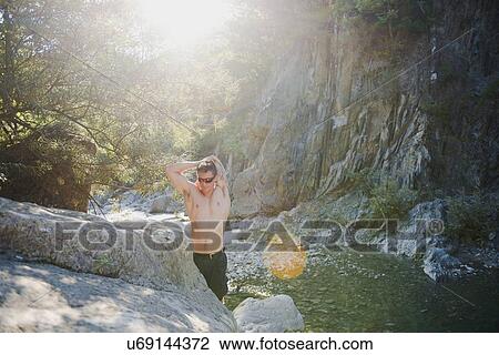 Stock Image - Man stretching by stream, Arezzo, Toscana, Italy. Fotosearch