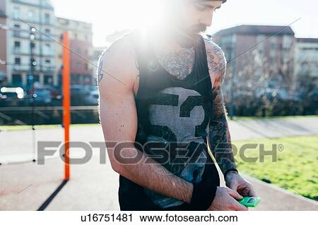 Stock Image - Man taking break in outdoor gym. Fotosearch