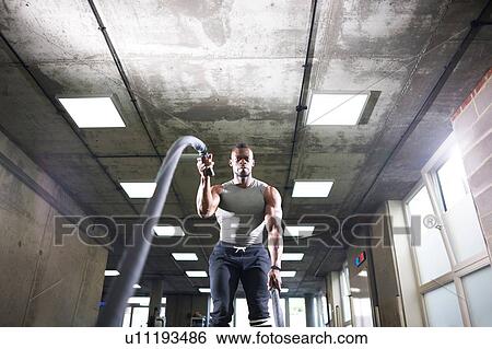Man Using Battle Ropes In Gym Stock Photograph U11193486