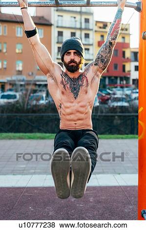 Stock Photo - Man using horizontal ladder in outdoor gym. Fotosearch