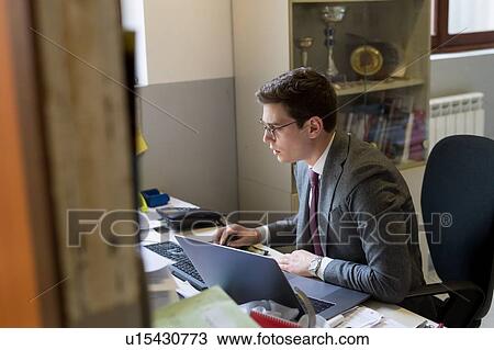 Man using laptop and desktop in office View Large Photo Image Stock Image - Man using laptop and desktop in office. Fotosearch
