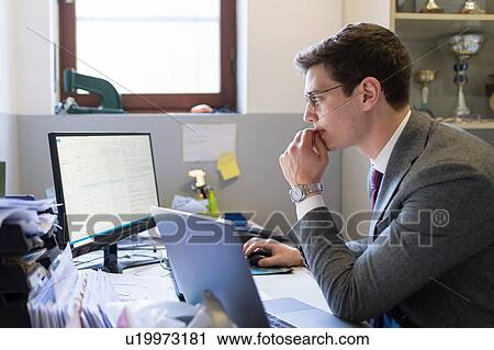 Man using laptop and desktop in office View Large Photo Image Stock Image - Man using laptop and desktop in office. Fotosearch
